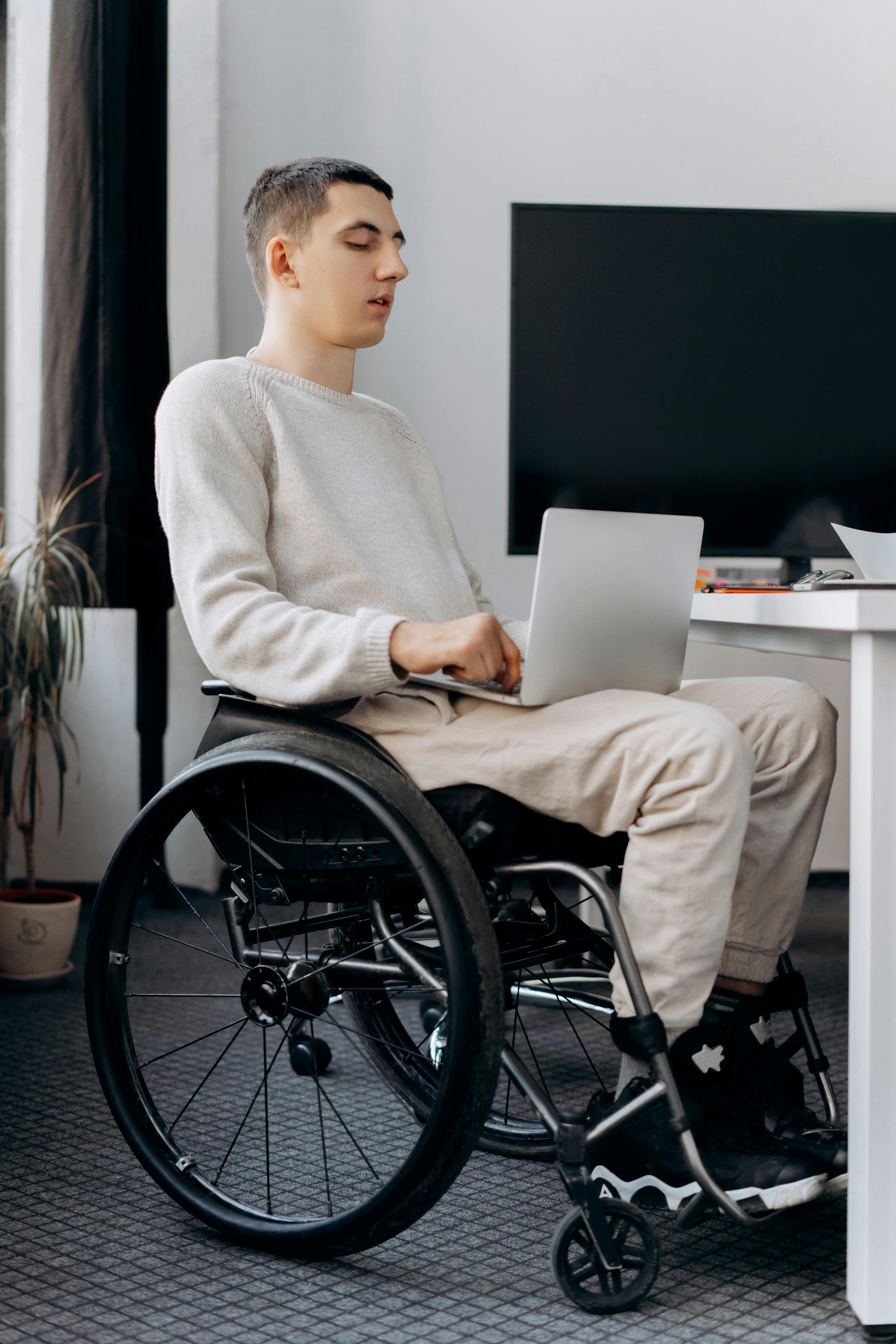 Disabled man in wheelchair working on computer.