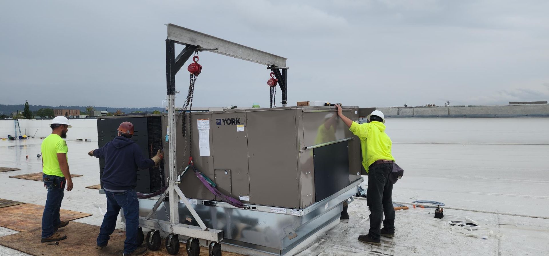 A group of men are working on an air conditioner on top of a roof.