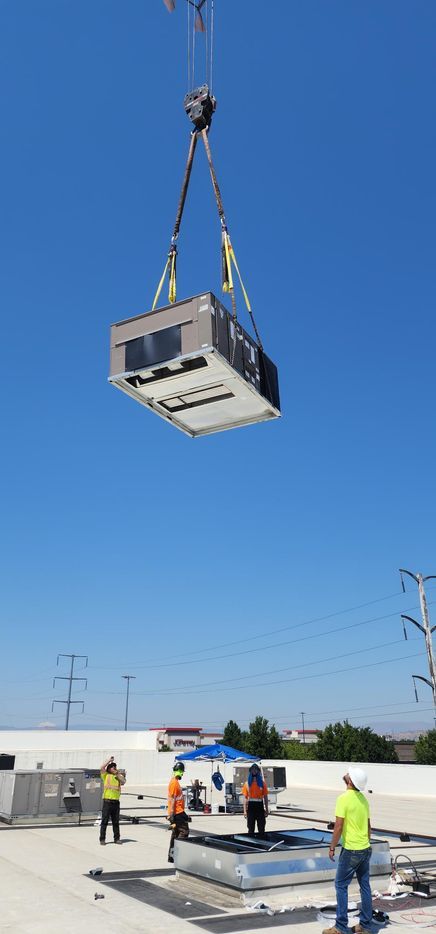 A crane is lifting a large piece of equipment into the air.