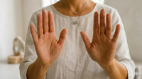 Two hands reaching toward each other over a blurred field of white flowers