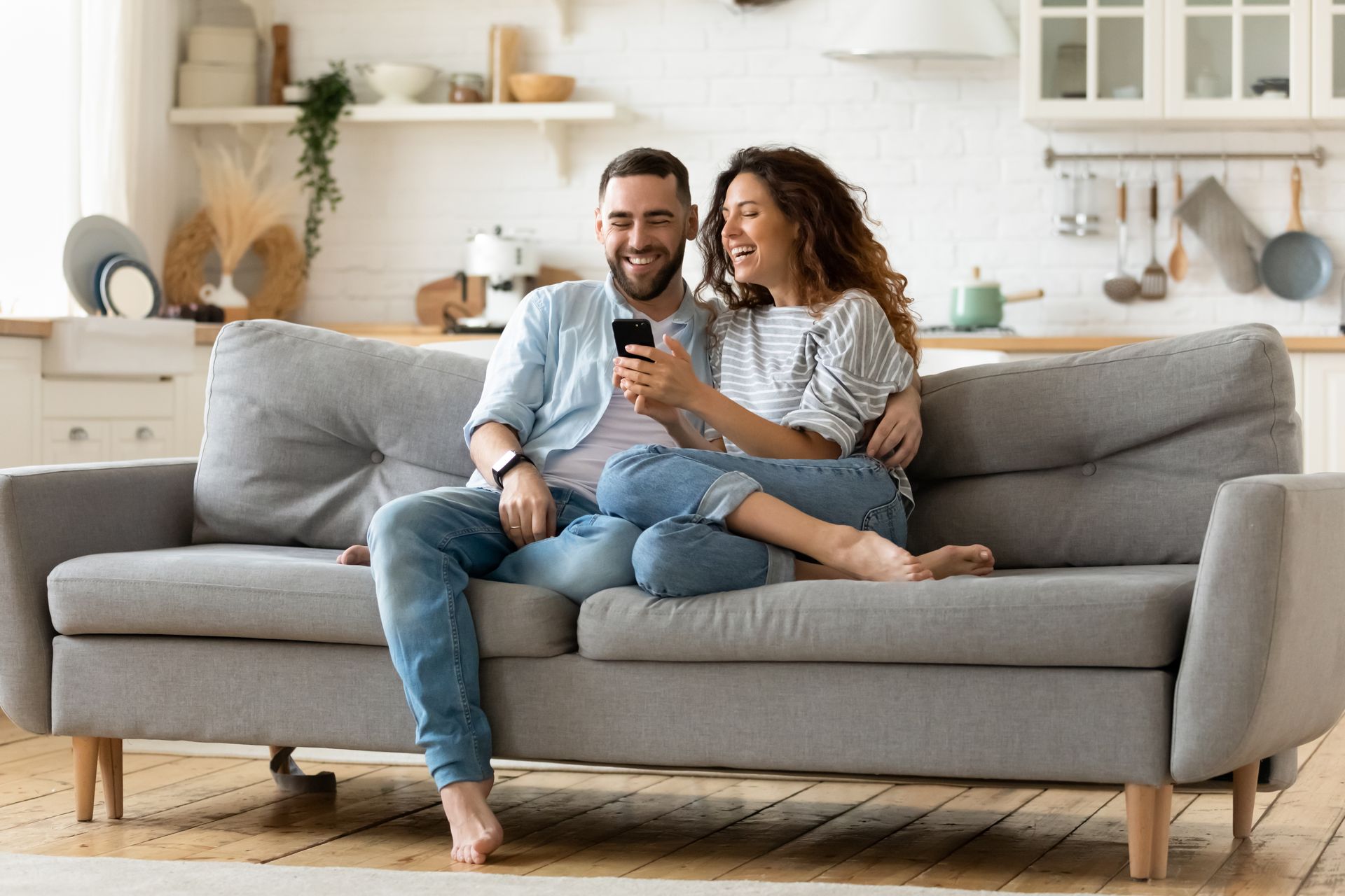 A man and a woman are sitting on a couch looking at a cell phone.