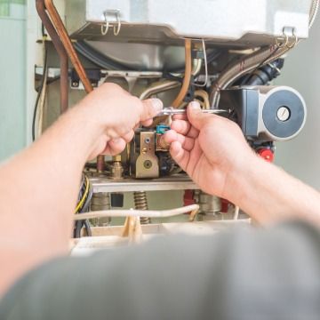 Hands tightening a cable inside an open machine with visible wiring and a blue motor