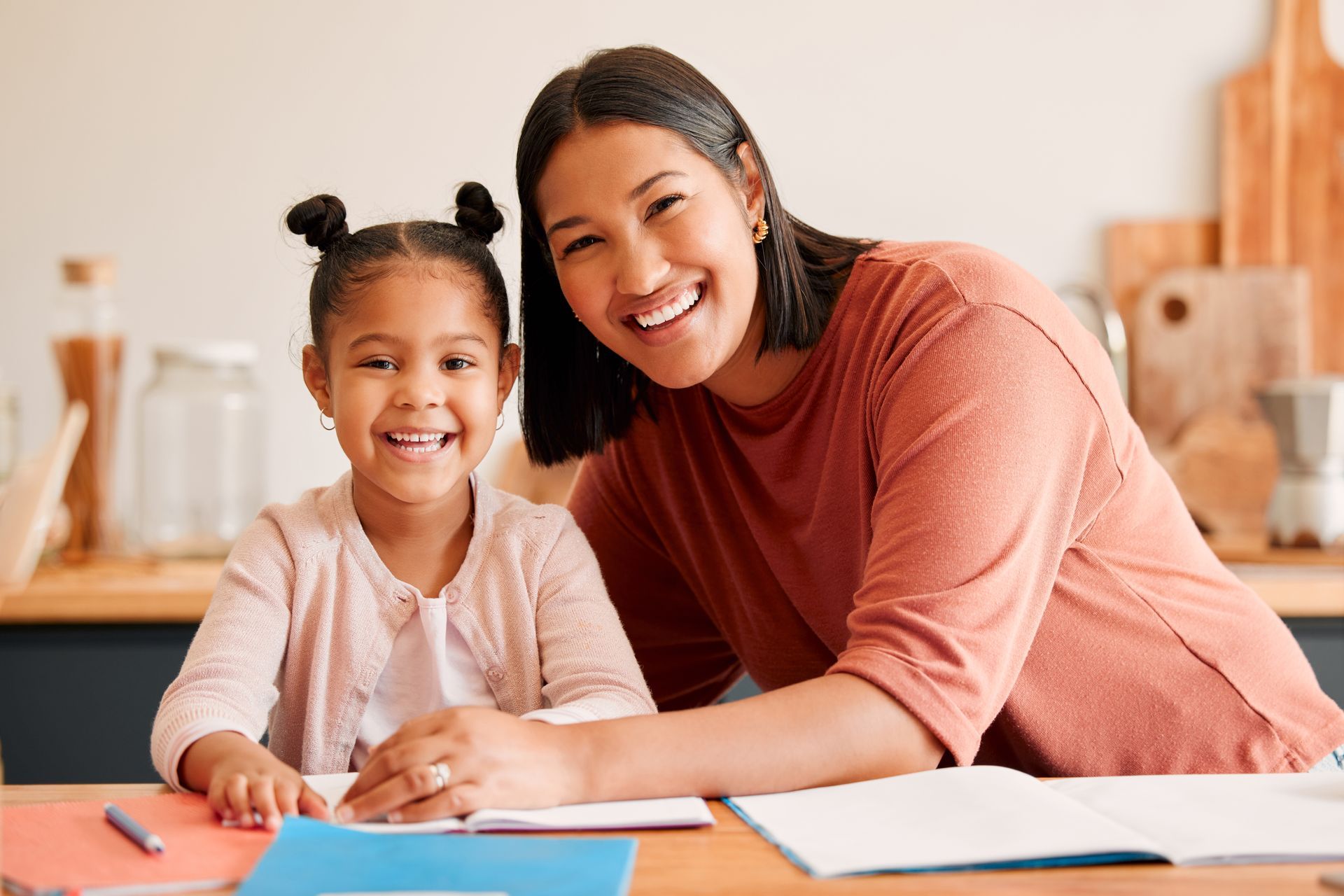 Woman and child smiling at the camera while at a table with books.