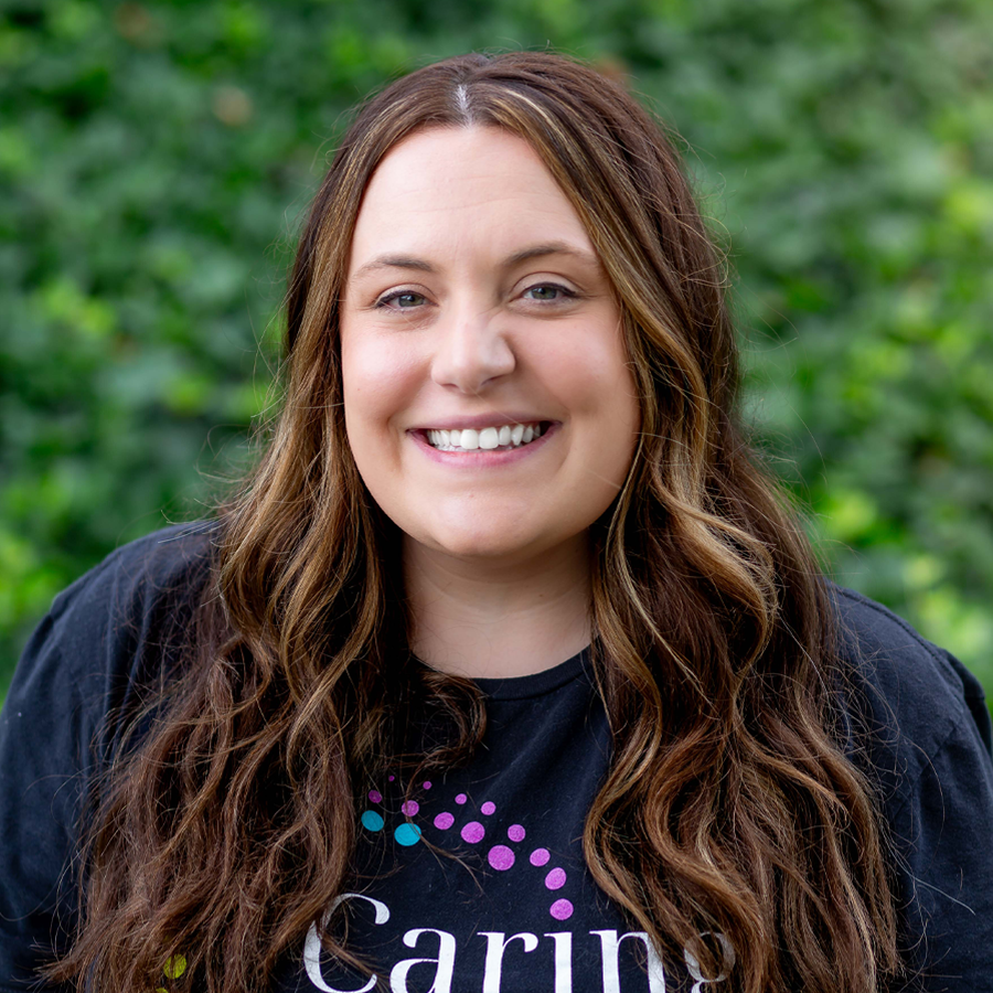 Woman with brown hair smiling, wearing black shirt with 