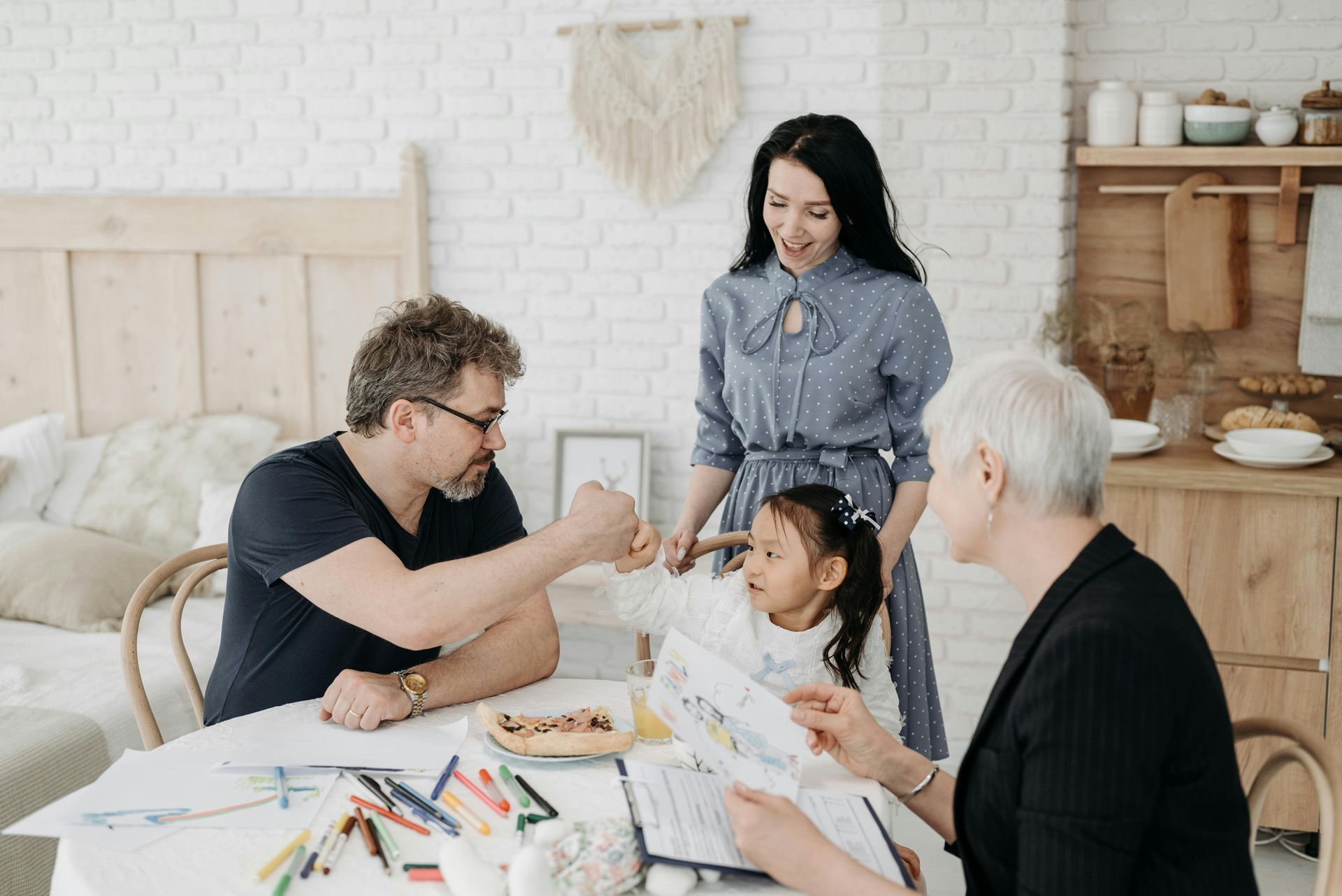 Woman and boy packing luggage together, smiling. Yellow top, white shirt, indoor setting.