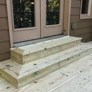 Wooden steps leading up to double doors on a deck.