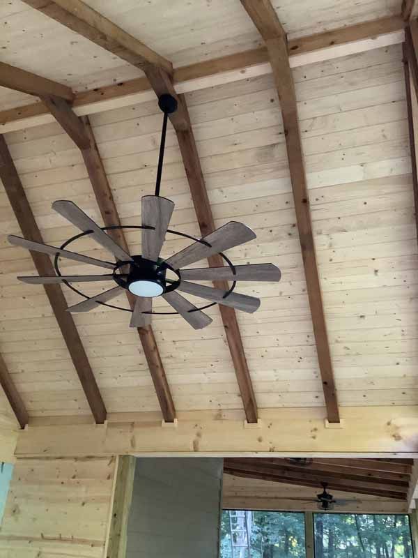 Ceiling fan with light fixture hanging from a wood-beamed ceiling.