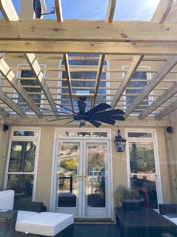 Pergola over glass doors and windows, outdoor seating area with a ceiling fan.