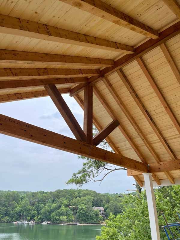 Wooden porch roof with a view of a lake and trees.