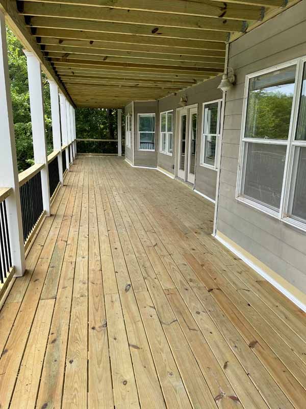 Wooden deck with a covered ceiling, overlooking a natural setting.