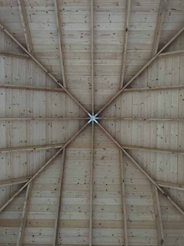 Wooden gazebo ceiling with radiating beams meeting at a central metal star-shaped connector.