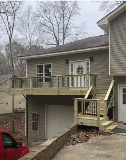 Two-story house with a wooden deck and stairs; garage below; tan siding.