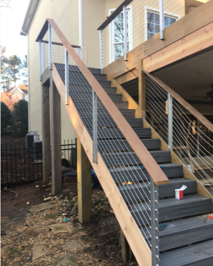 Wooden deck with gray stairs and metal railing, leading down to a yard.