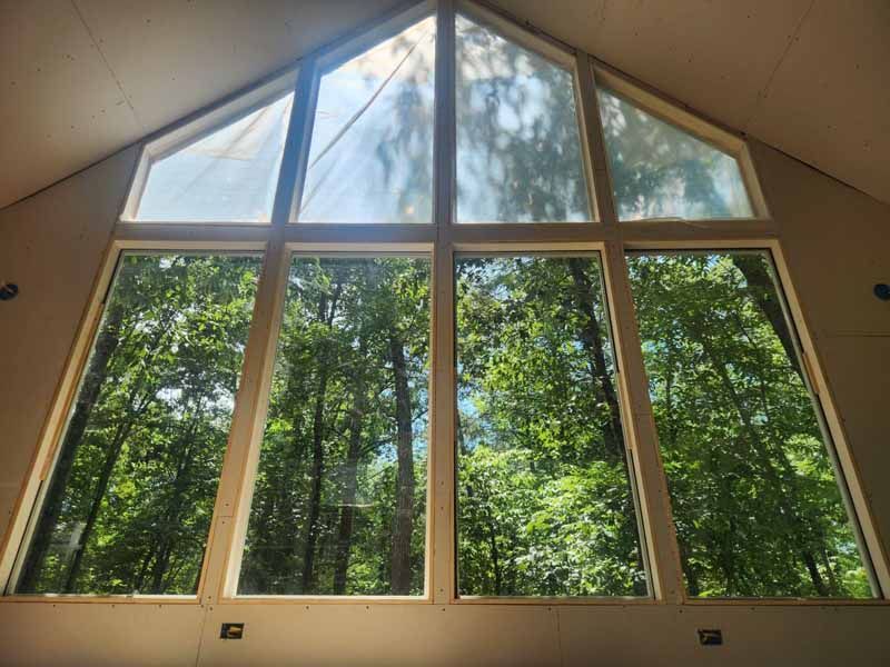 Large window with clear panes, showing lush green trees and sunlight streaming through.