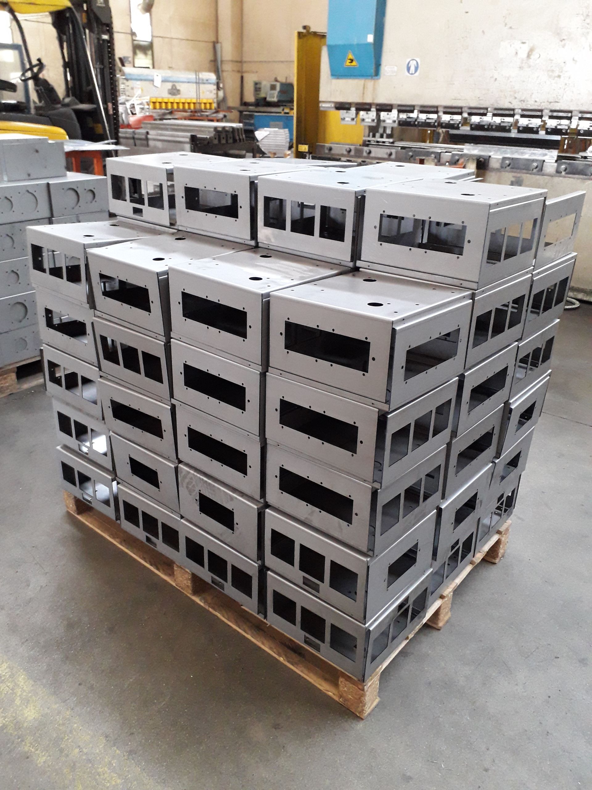 Casse metalliche grigie impilate su un pallet di legno in un magazzino industriale.