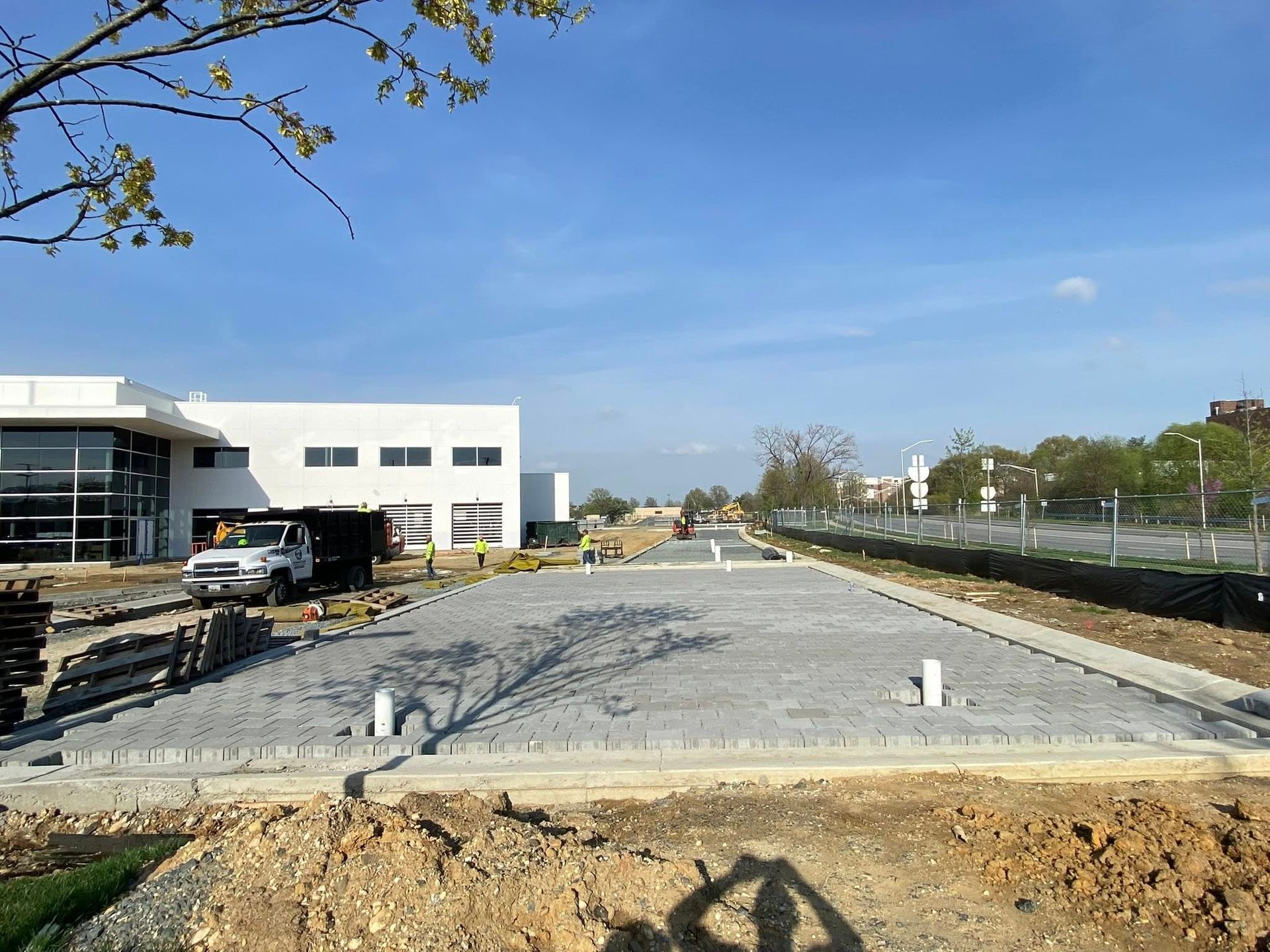 Construction site with gravel foundation, white building on left, and clear blue sky