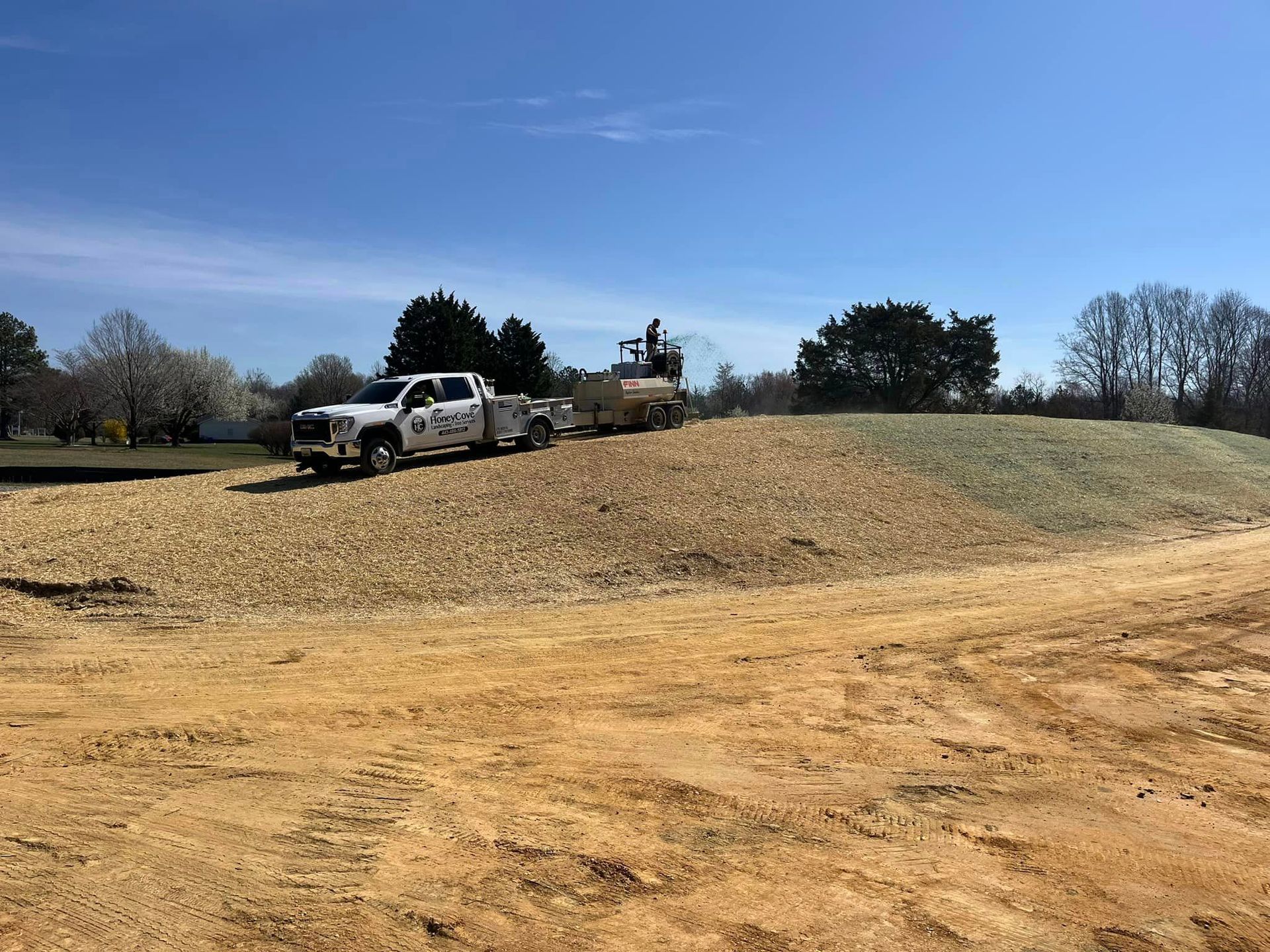 Two trucks are parked on top of a dirt hill.