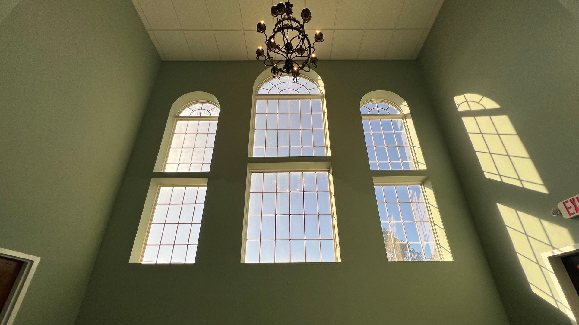Looking up at a chandelier hanging from the ceiling in a room with arched windows
