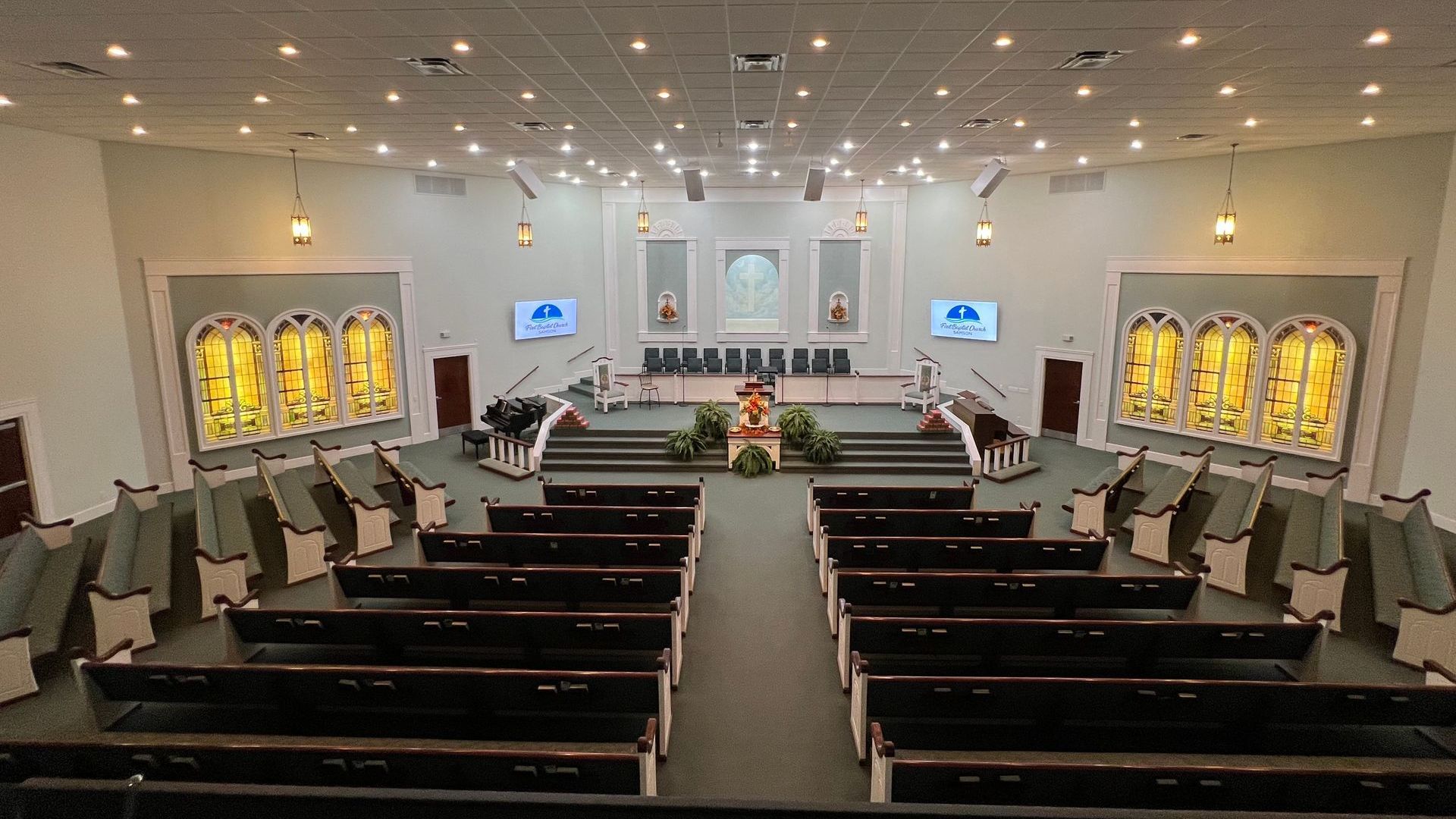 The inside of a church with rows of benches and stained glass windows.