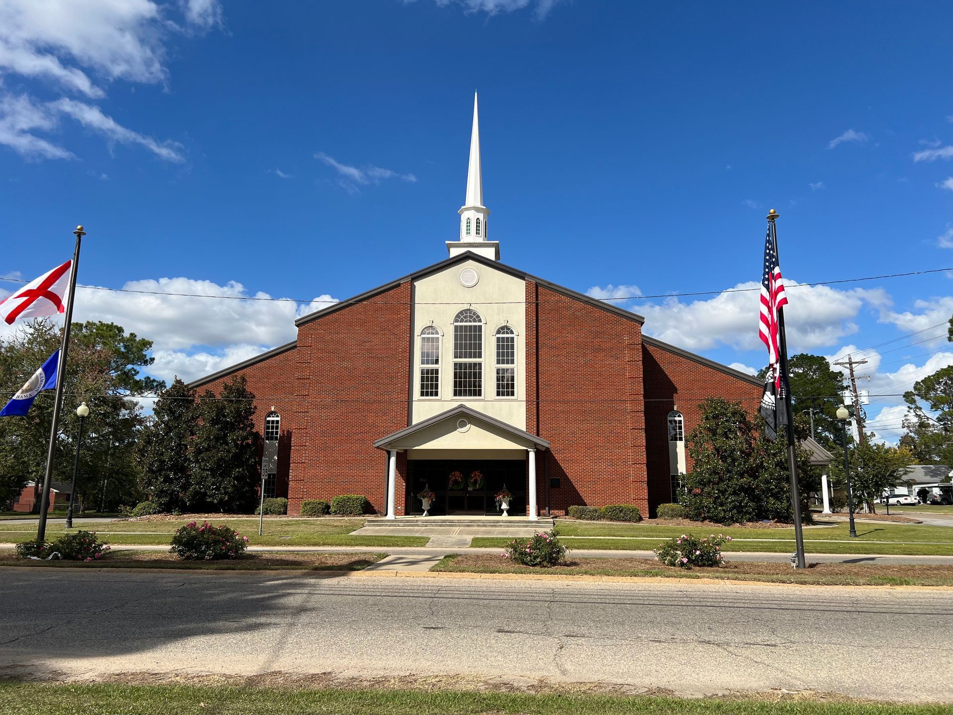 First Baptist Church Samson with flags in front of it on a sunny day