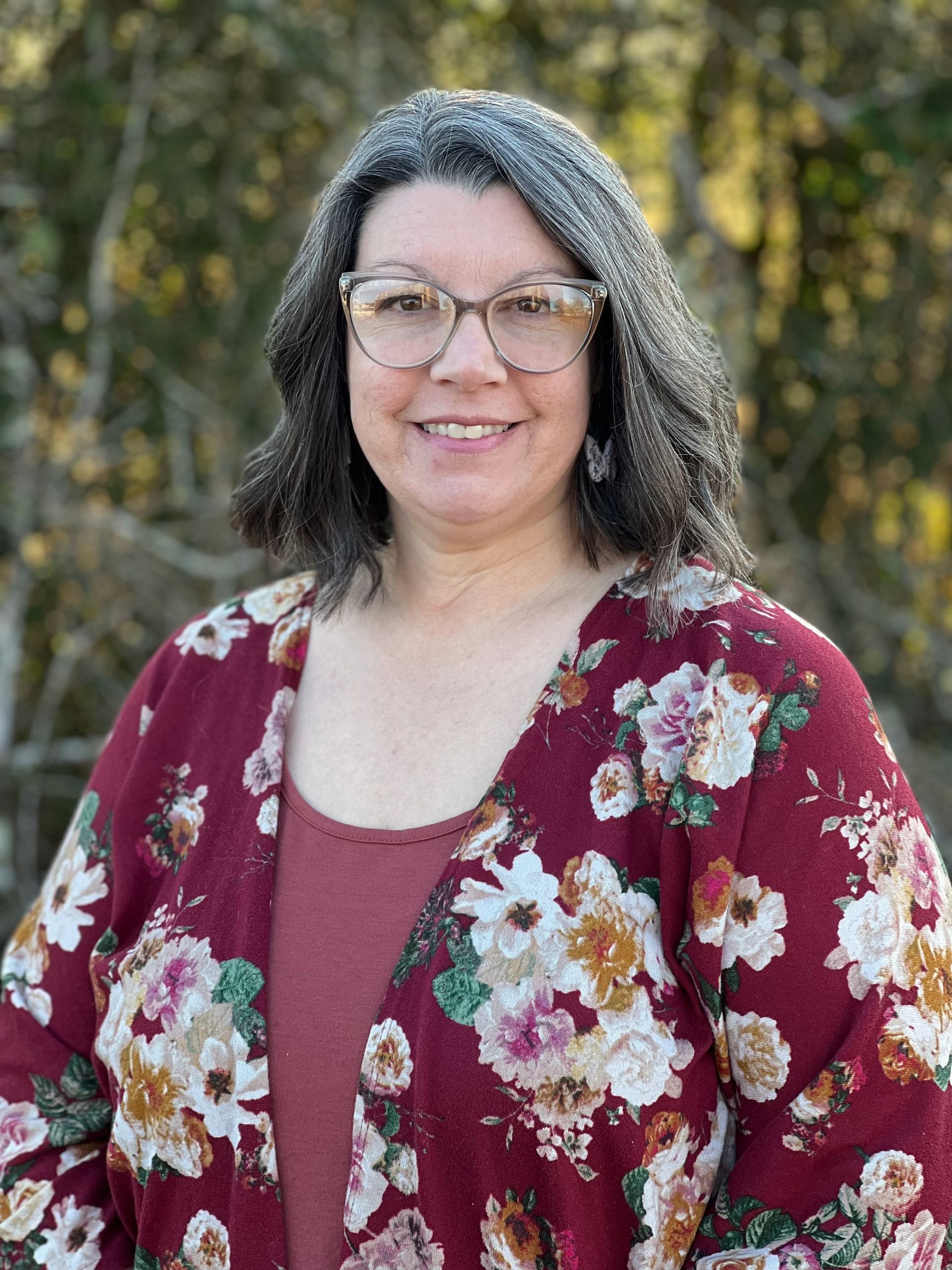 Kimberly in a floral jacket is smiling for the camera.