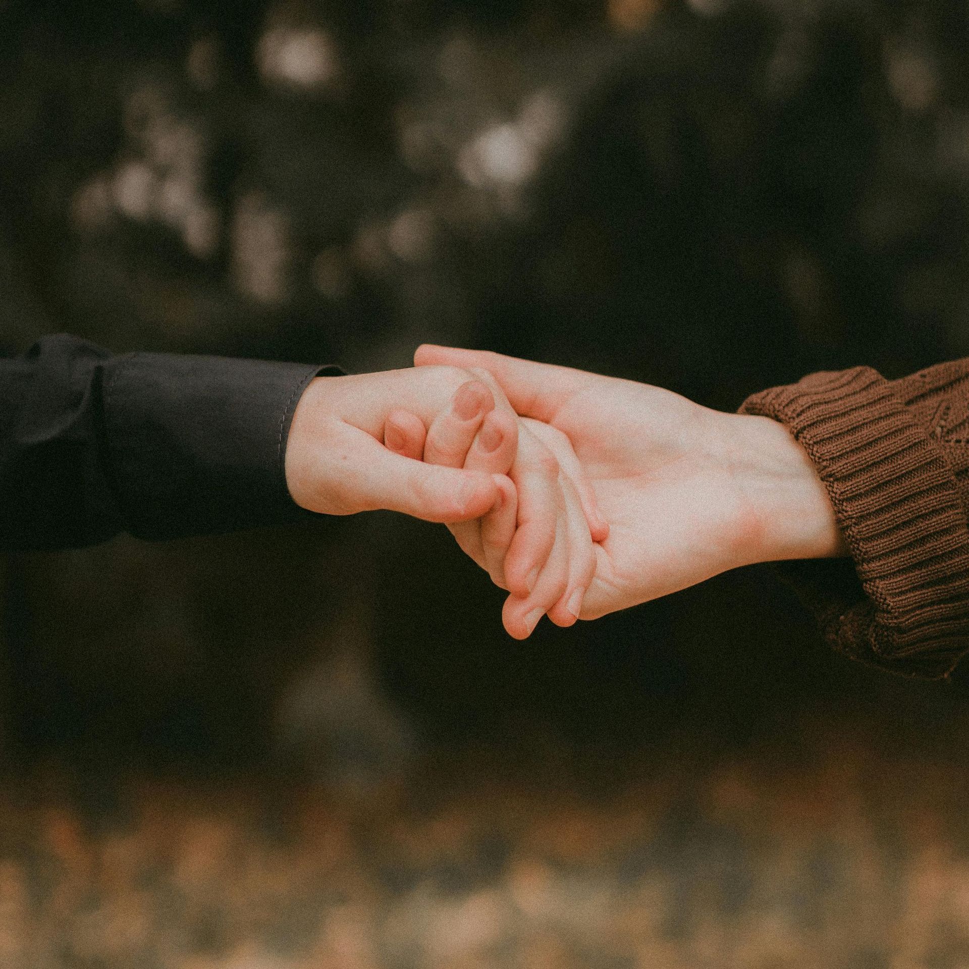 A man and a woman are holding hands in a park.