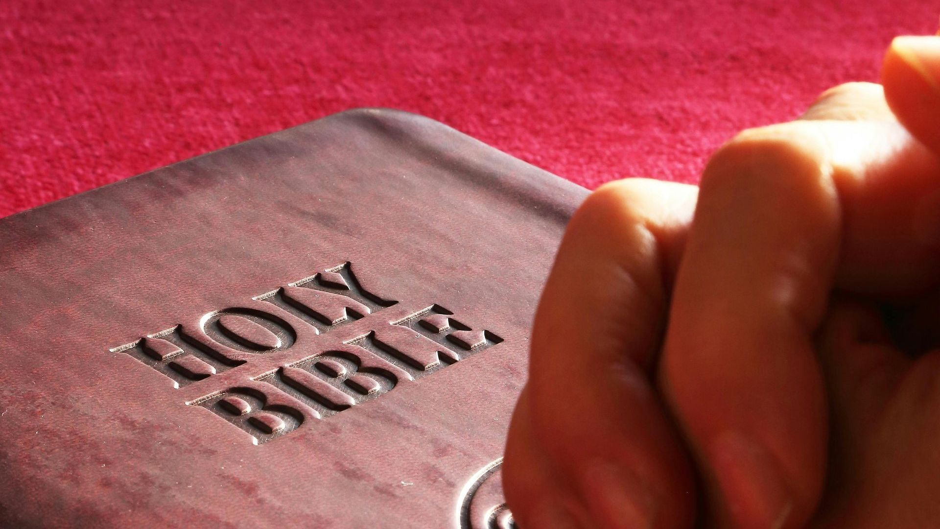 A person is praying in front of a holy bible