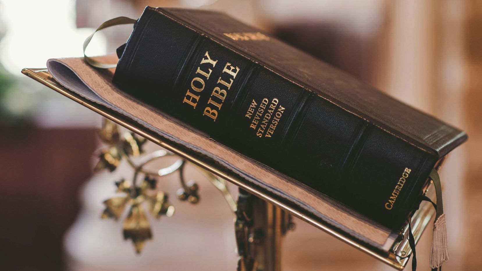 A holy bible is sitting on a stand in a church.
