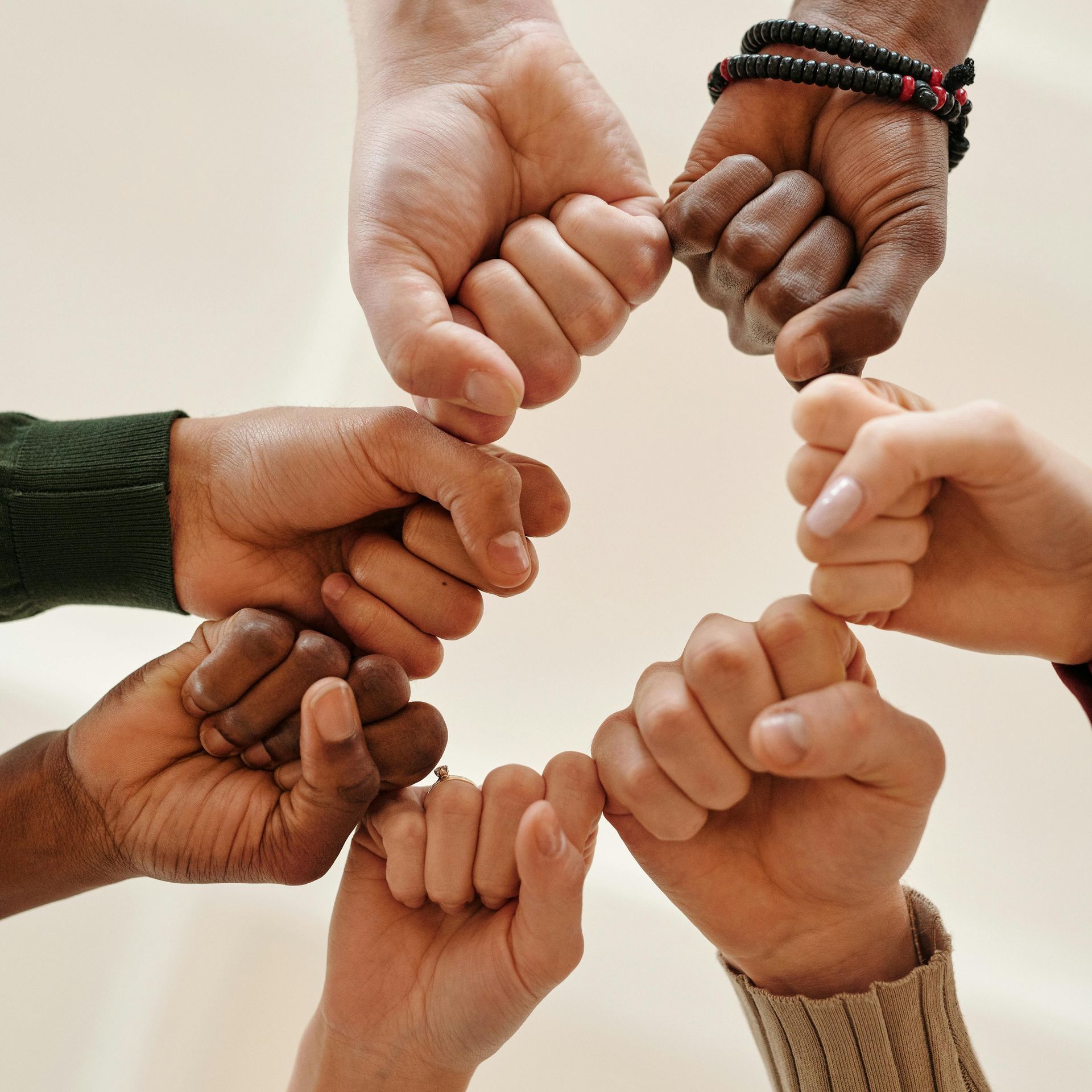A group of people are putting their fists together in a circle