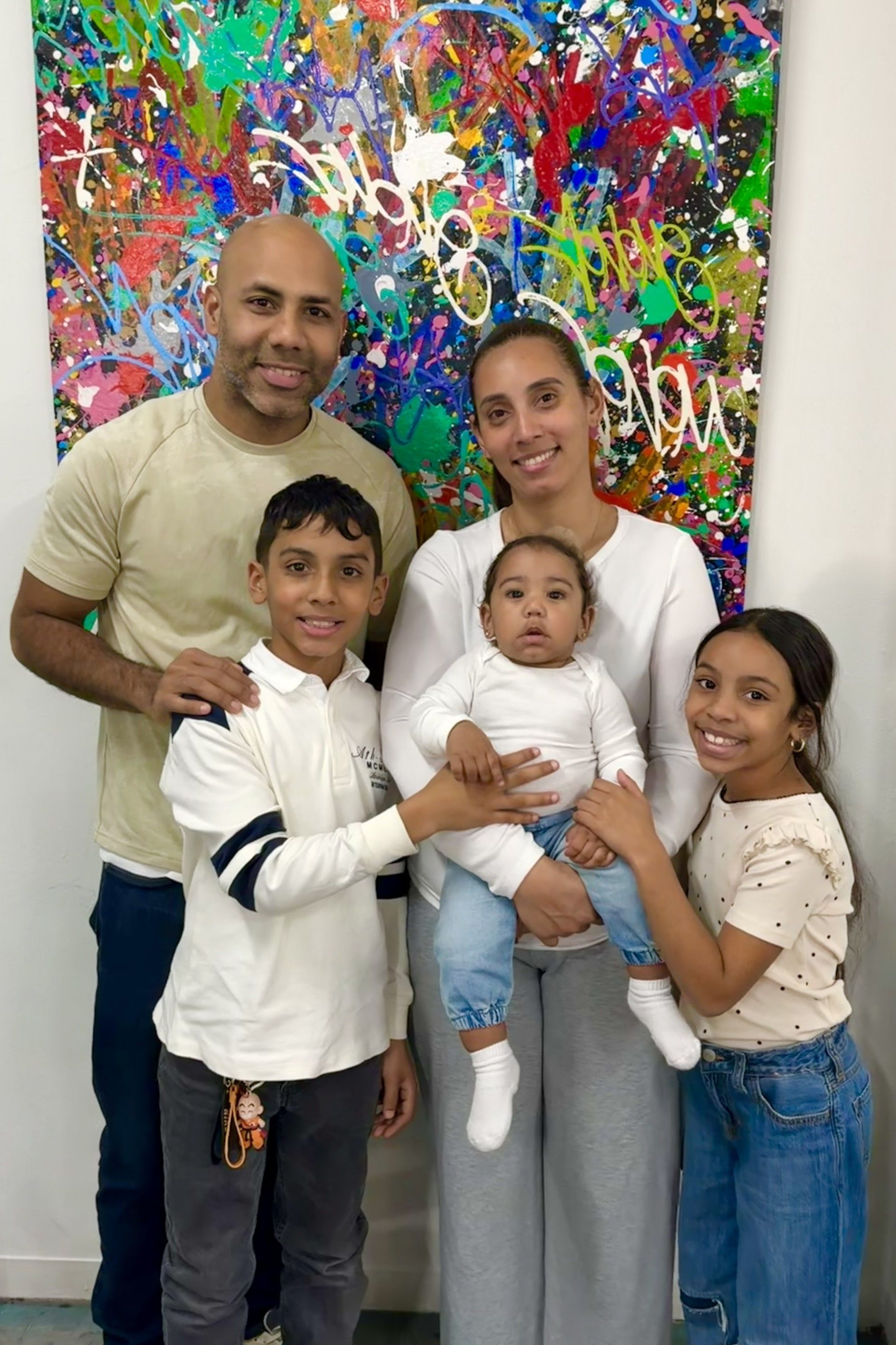 A family standing in a medical office with a bright colored painting in the background.