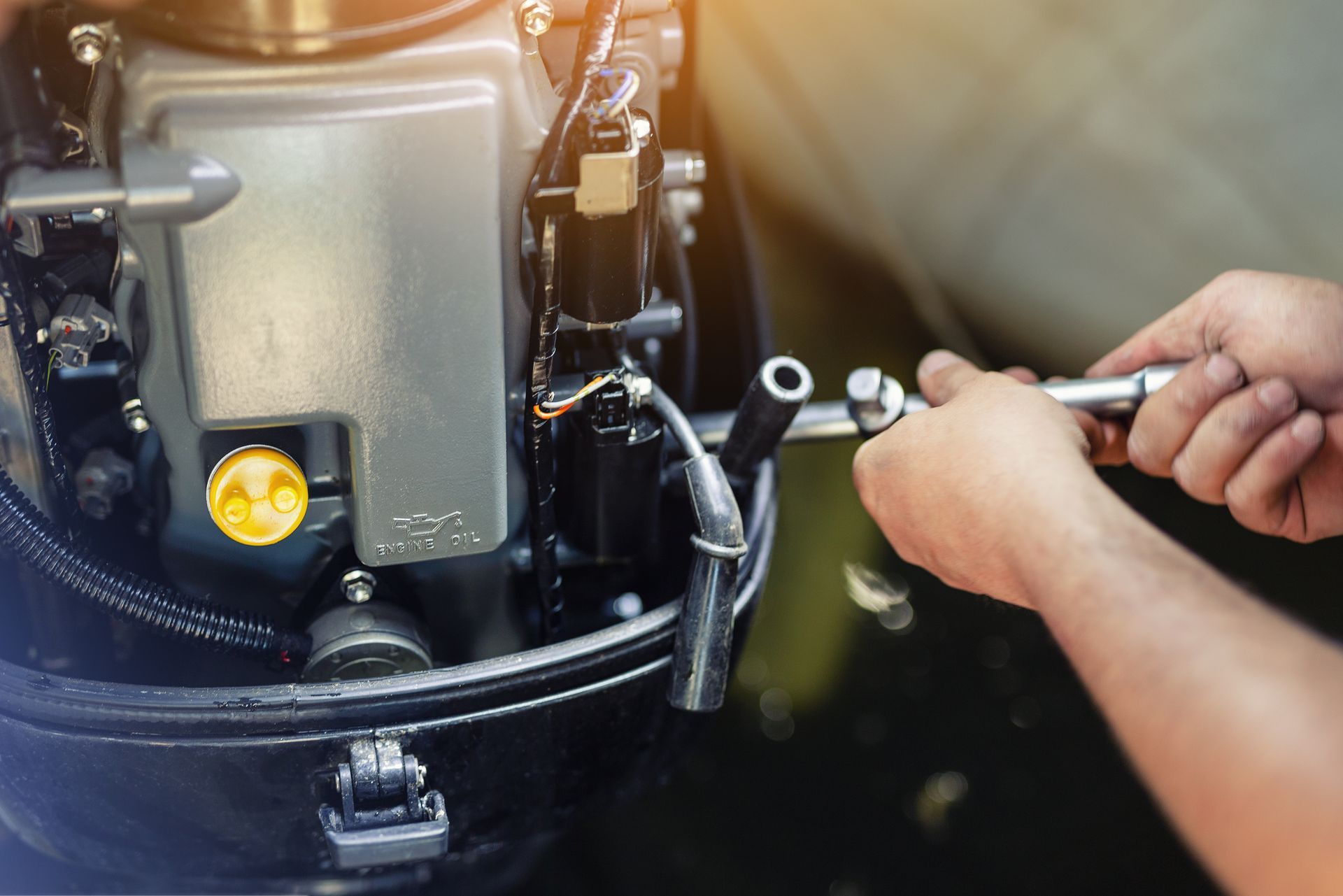 A person is working on a boat engine with a wrench.