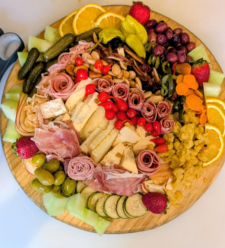 A large artisan charcuterie board with meats, cheeses, fruit, pickled vegetables, and nuts