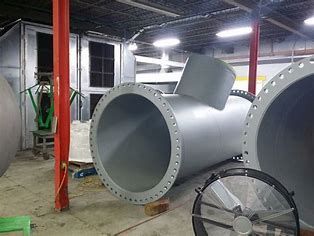 A bunch of metal pipes are sitting in a room in a factory.