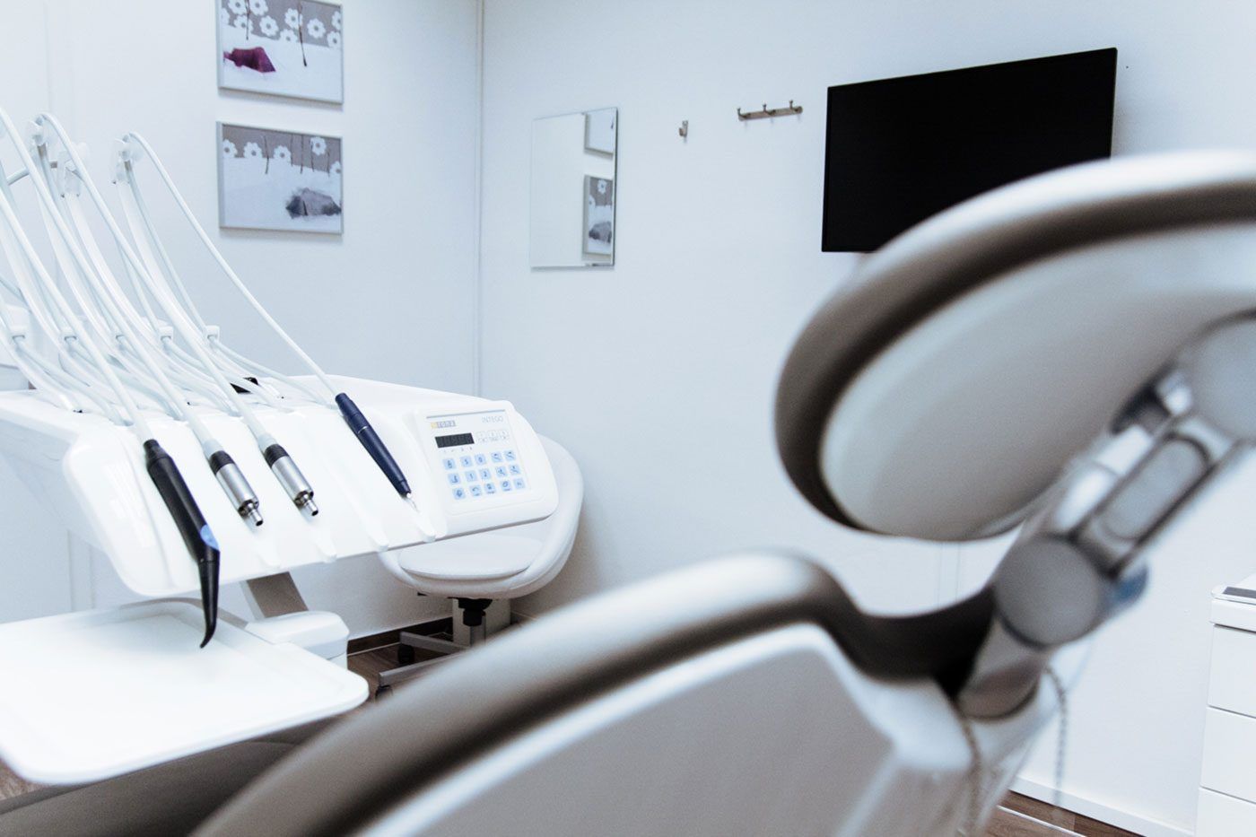 A dental chair in a dental office with a monitor on the wall
