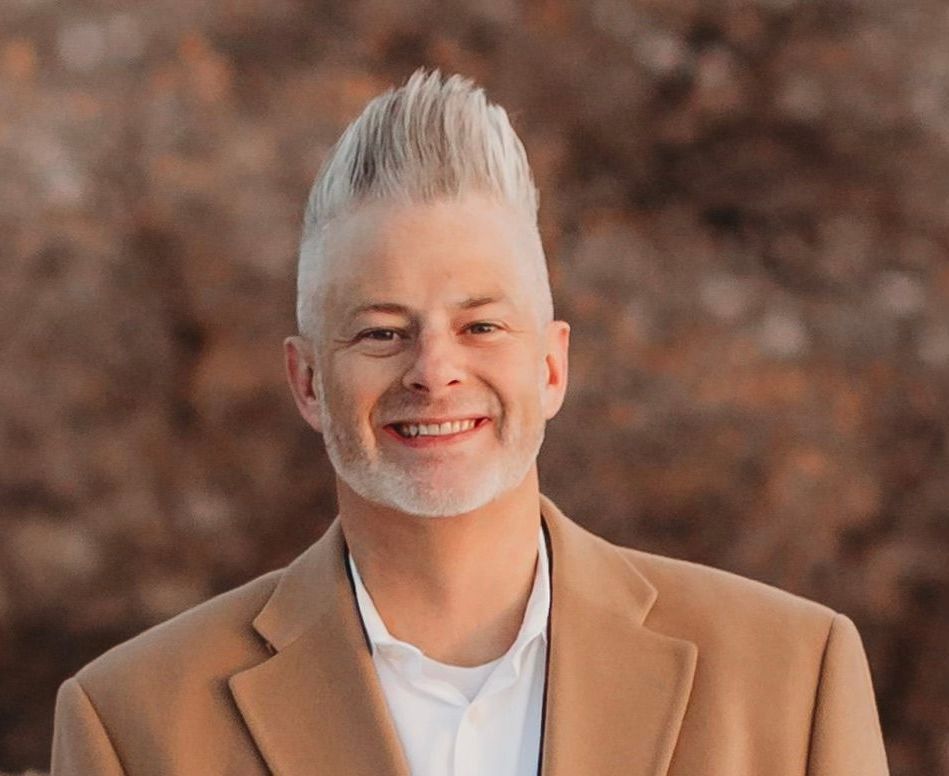 A man with a beard and mohawk is smiling for the camera.