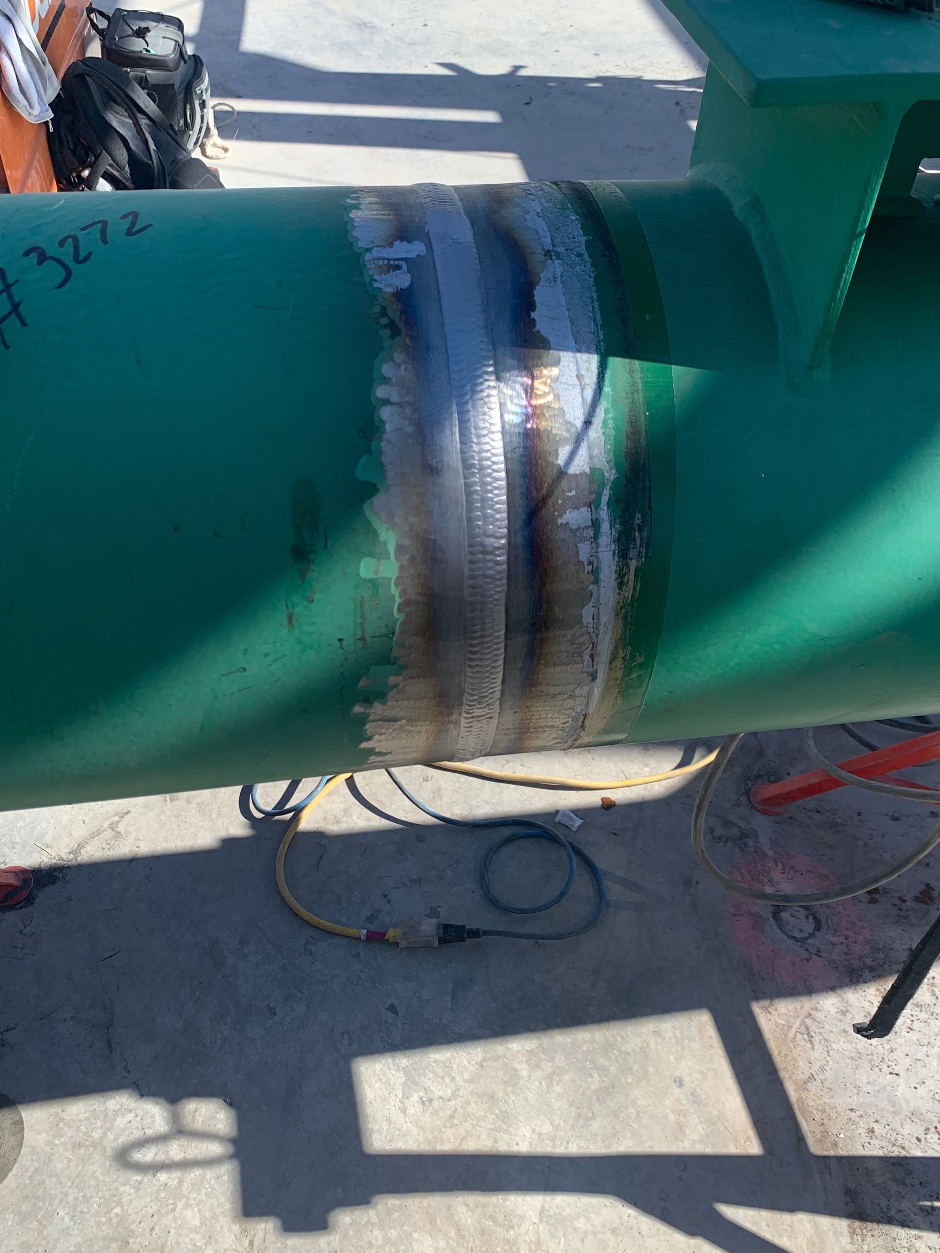 A green pipe with a hole in it is sitting on the ground.