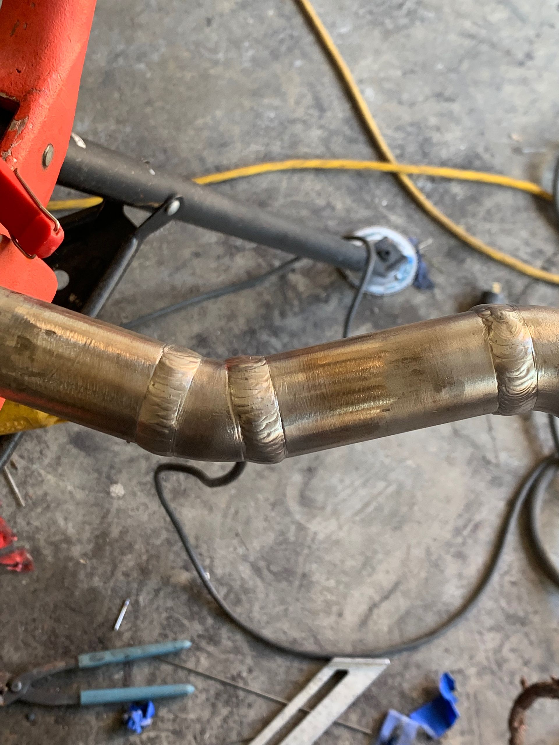 A close up of a metal pipe being worked on in a garage.