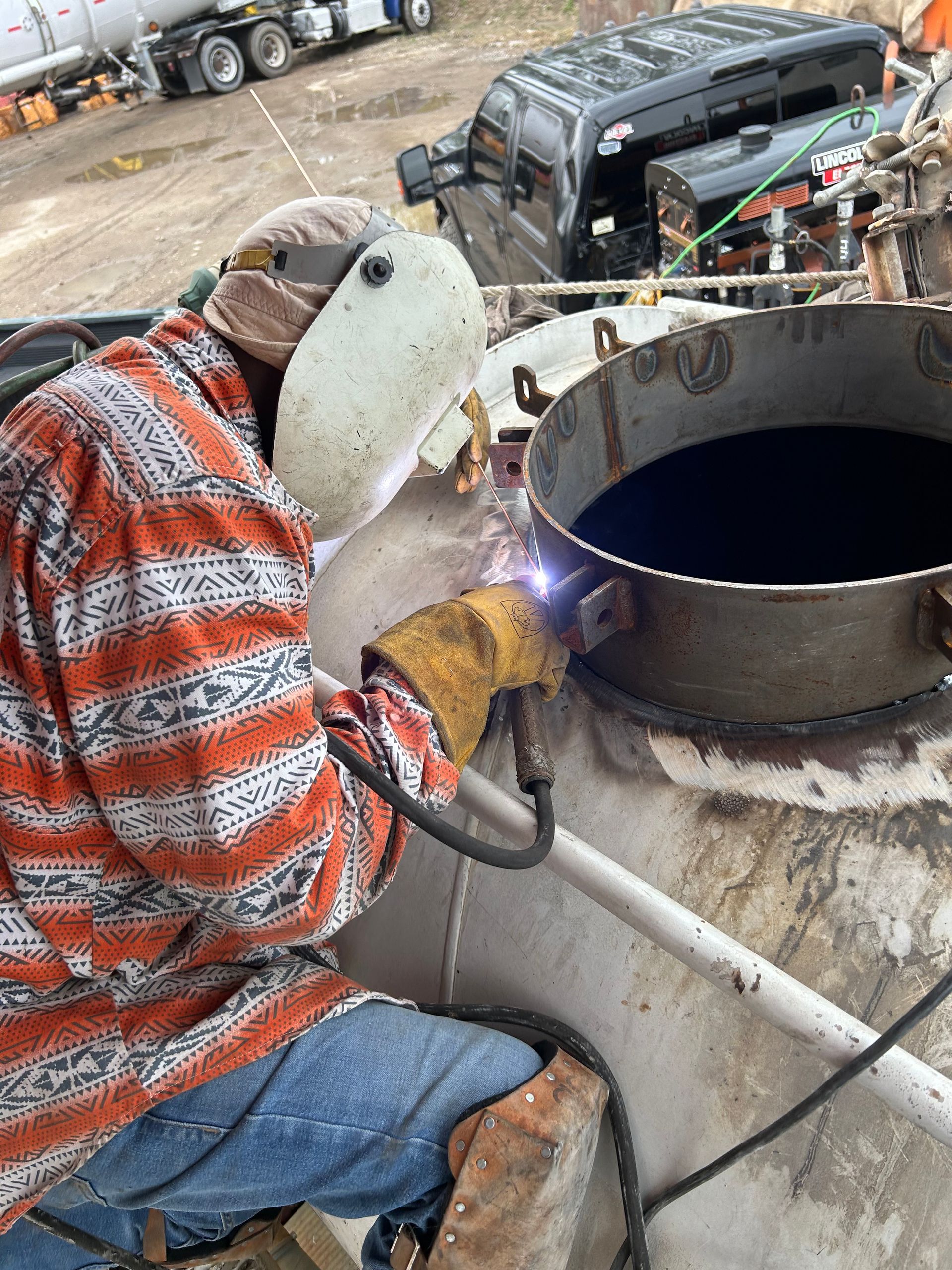 A man wearing a welding helmet is welding a metal object.