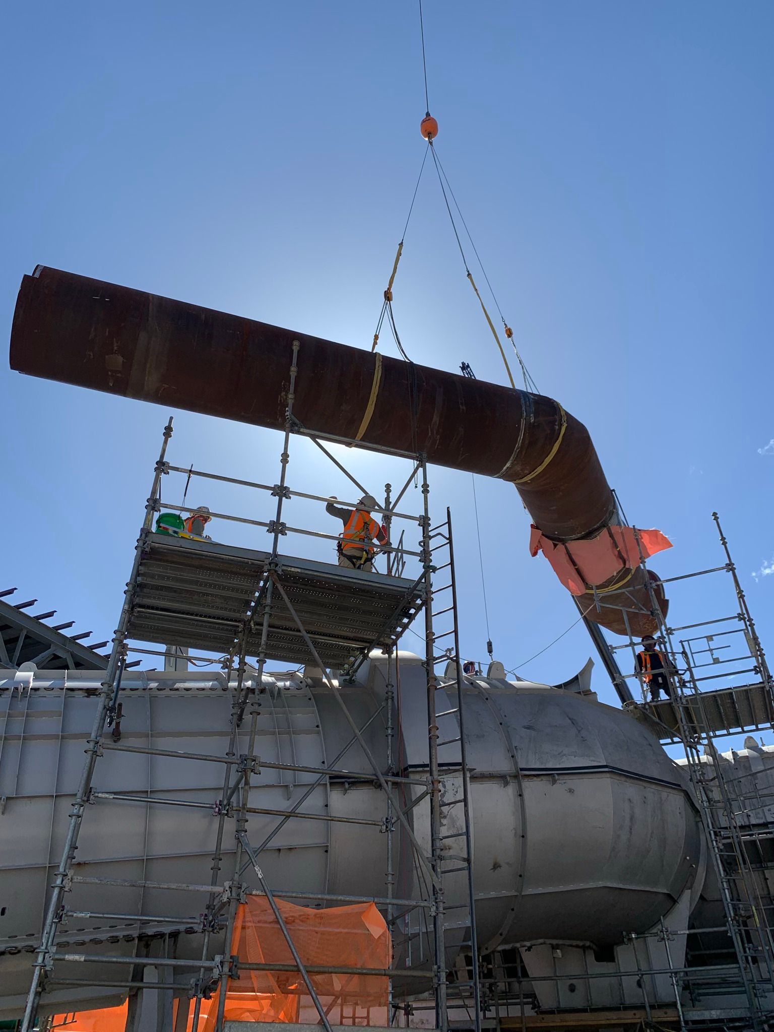A large pipe is being lifted by a crane