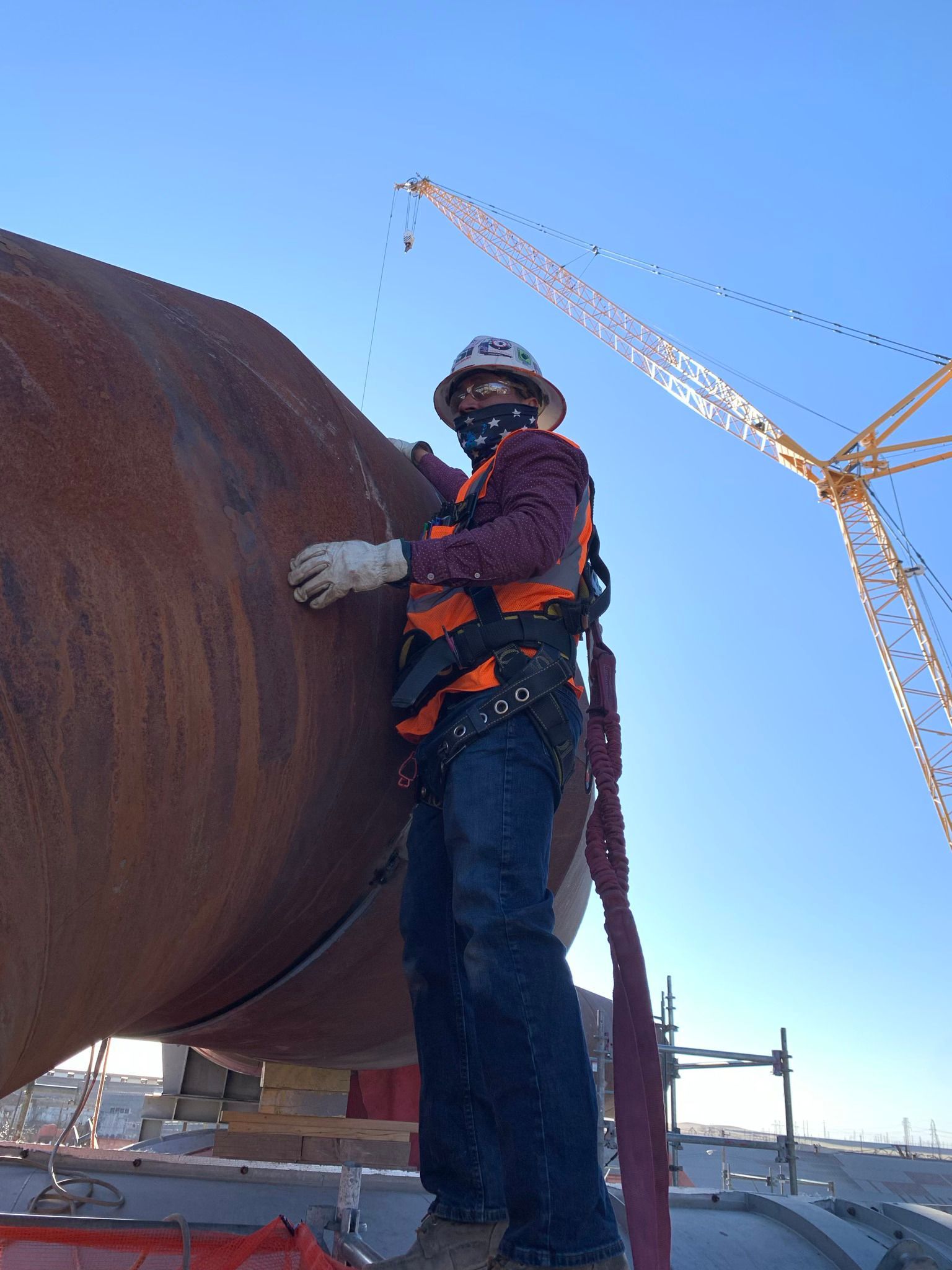 A man wearing a hard hat and safety vest is standing next to a large pipe.