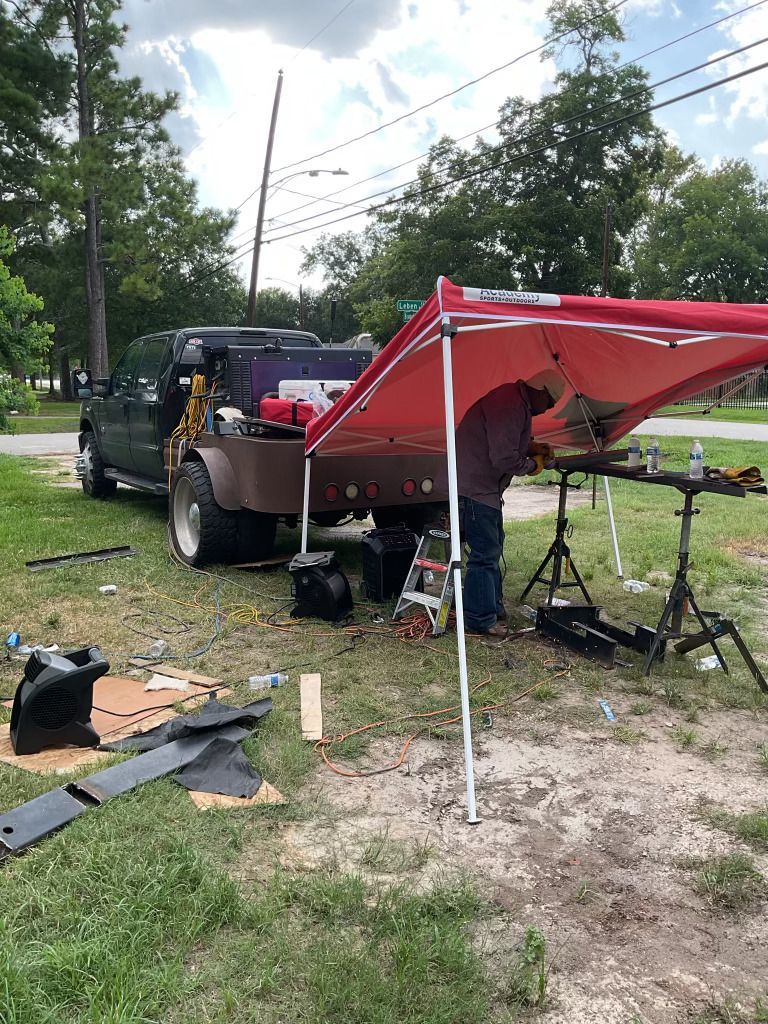 A man is standing under a red tent next to a truck.