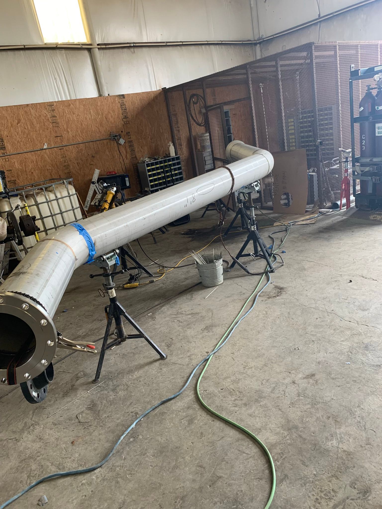 A large pipe is sitting on a tripod in a warehouse.