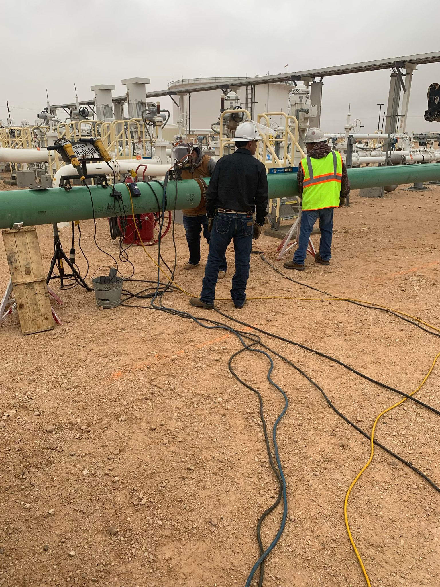 A group of men are working on a pipe in a field.