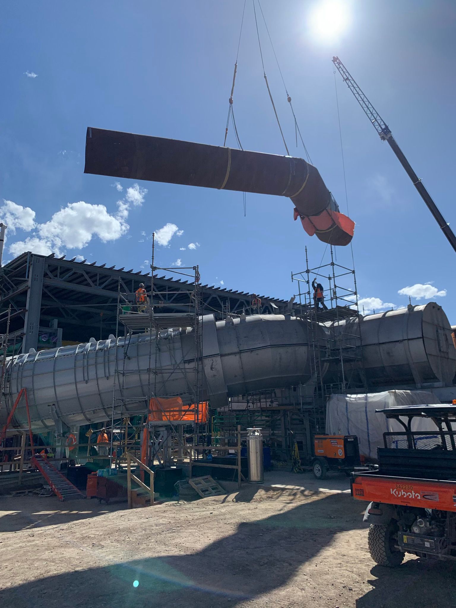 A large pipe is being lifted by a crane at a construction site.