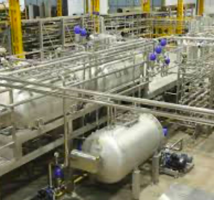 A factory filled with lots of stainless steel pipes and tanks.