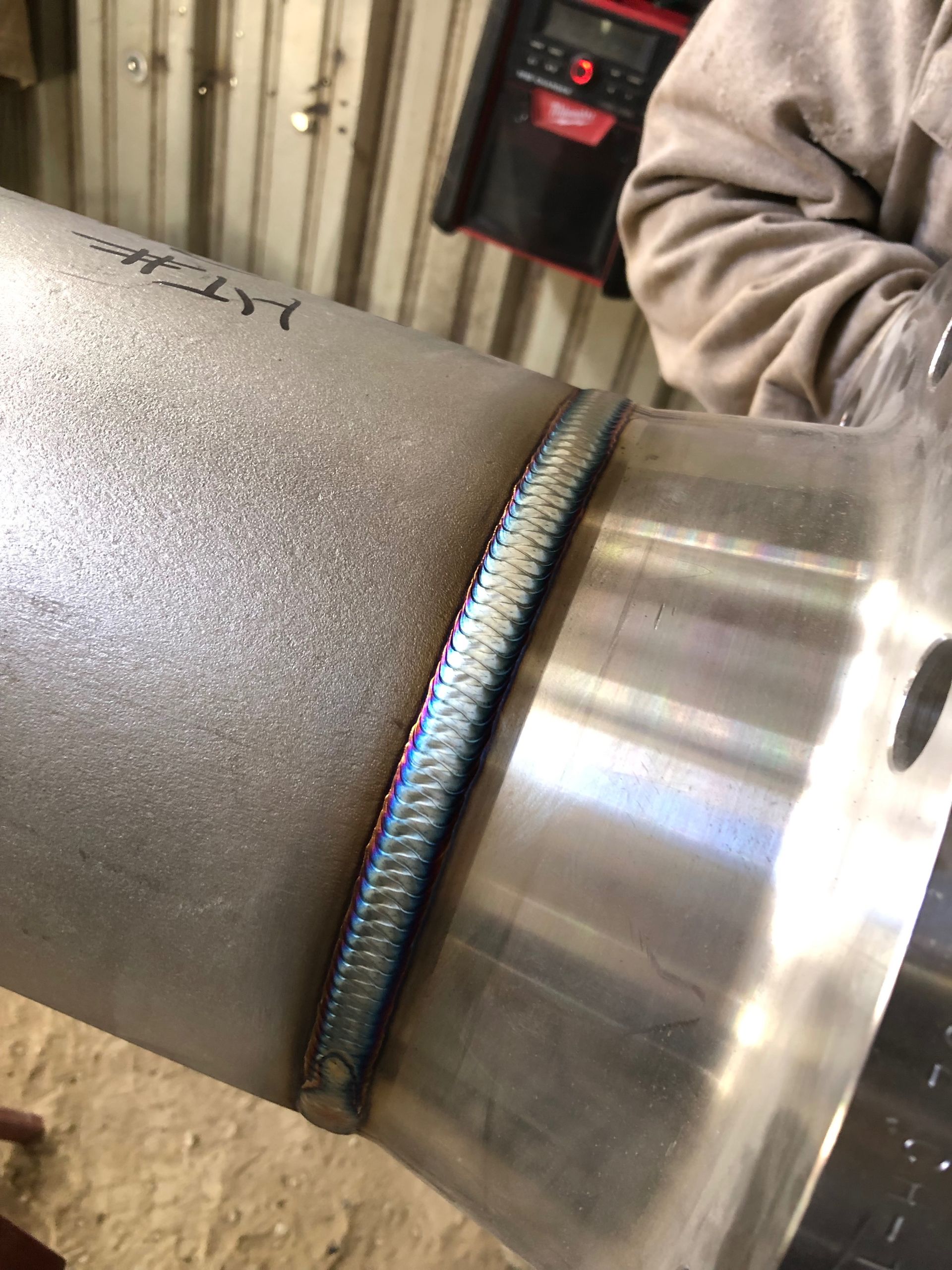 A close up of a person welding a metal pipe.