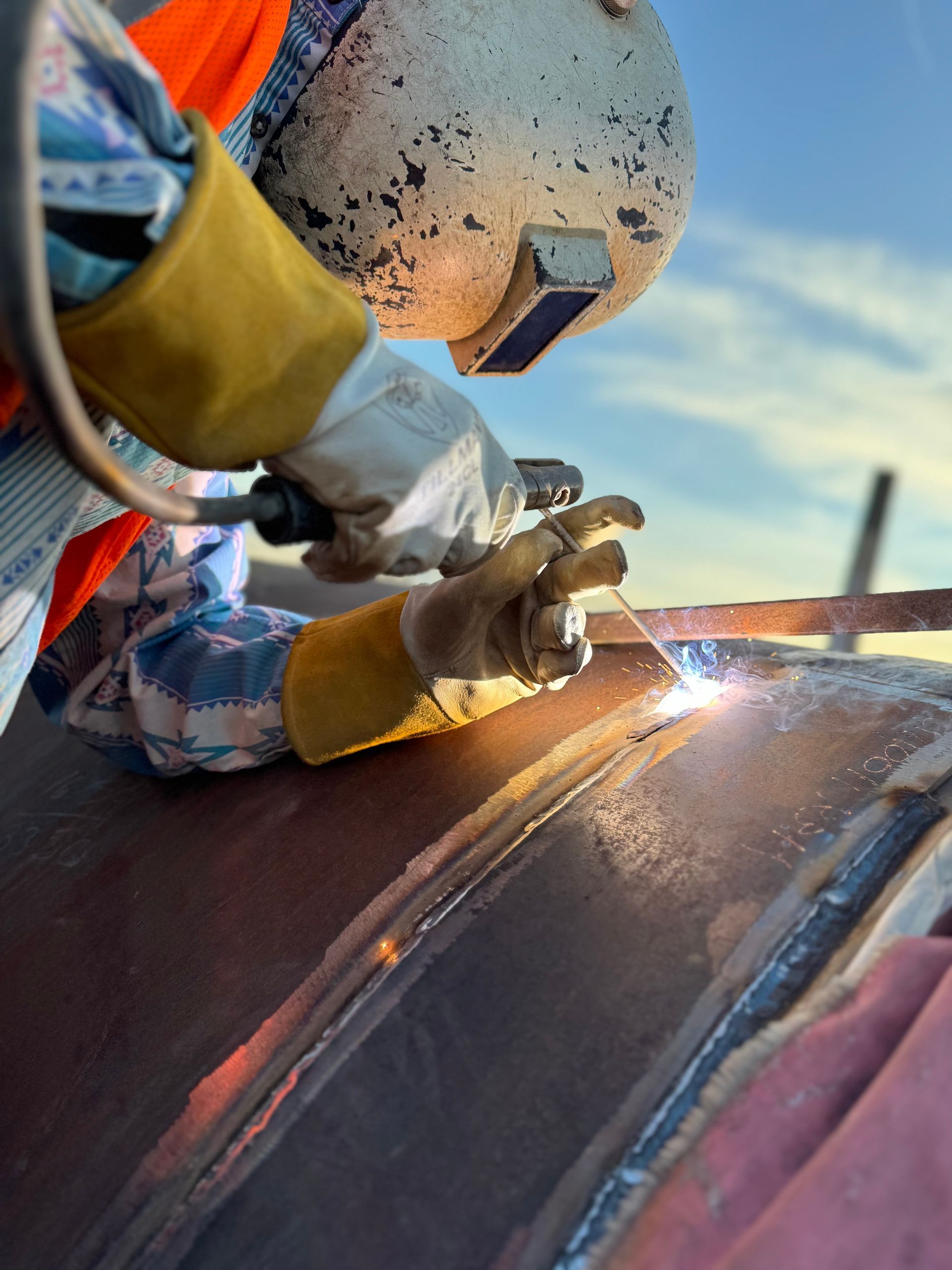 A man wearing a helmet is welding a piece of metal.