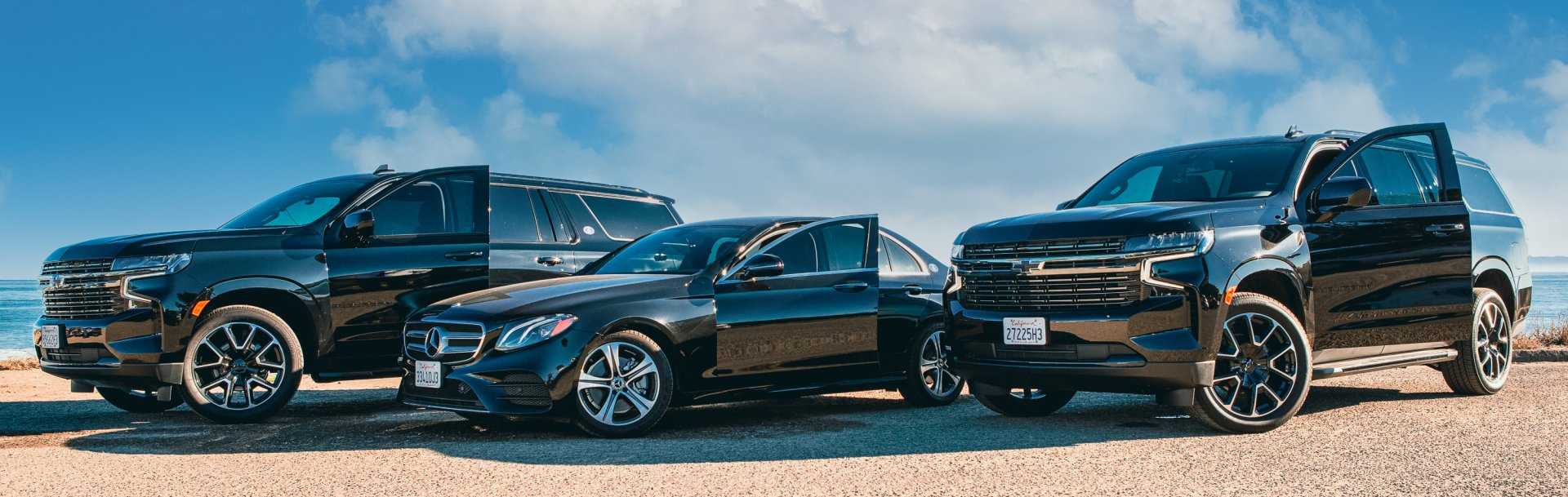 three black cars are parked next to each other on a beach .