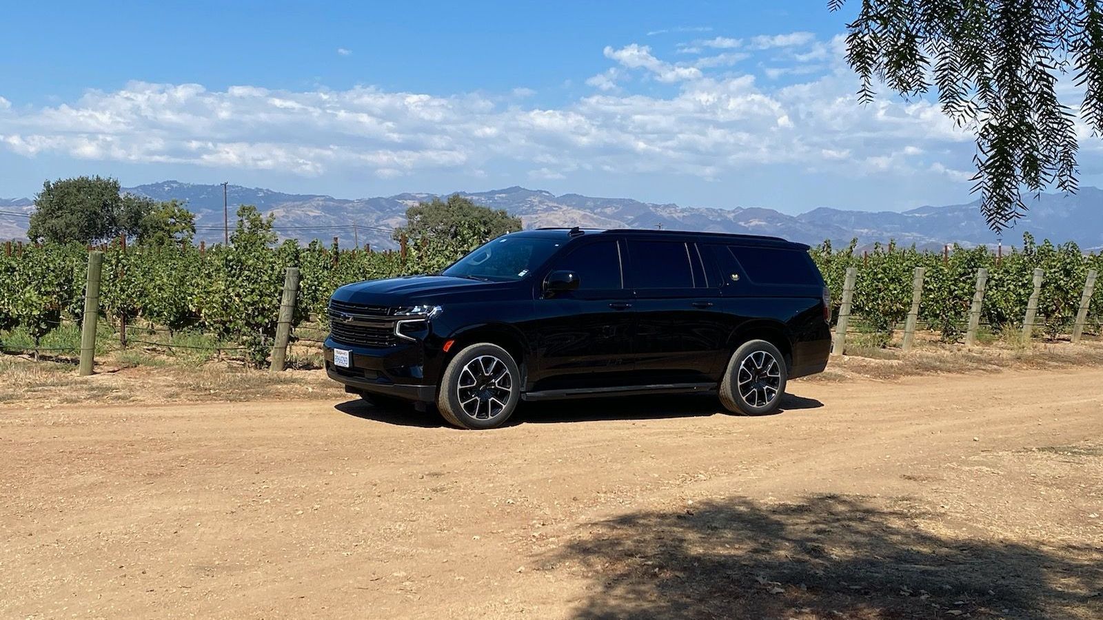 A black SUV is parked in the middle of a dirt field.