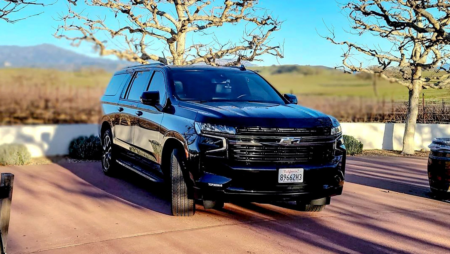 a black suv is parked in a driveway next to a field .